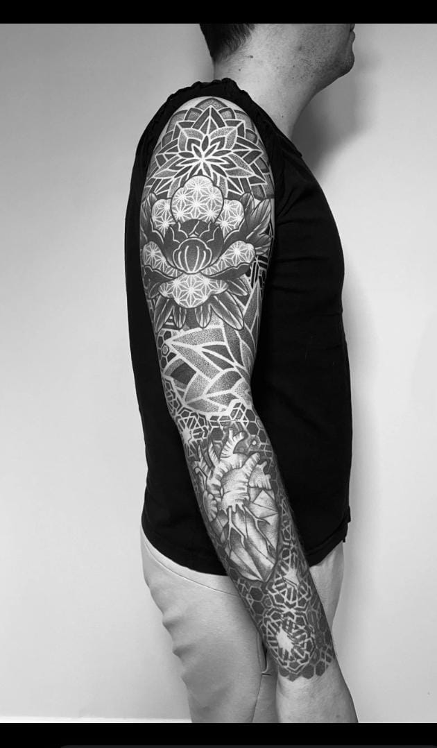 Tattoo artist working on a detailed bold sleeve design in studio
